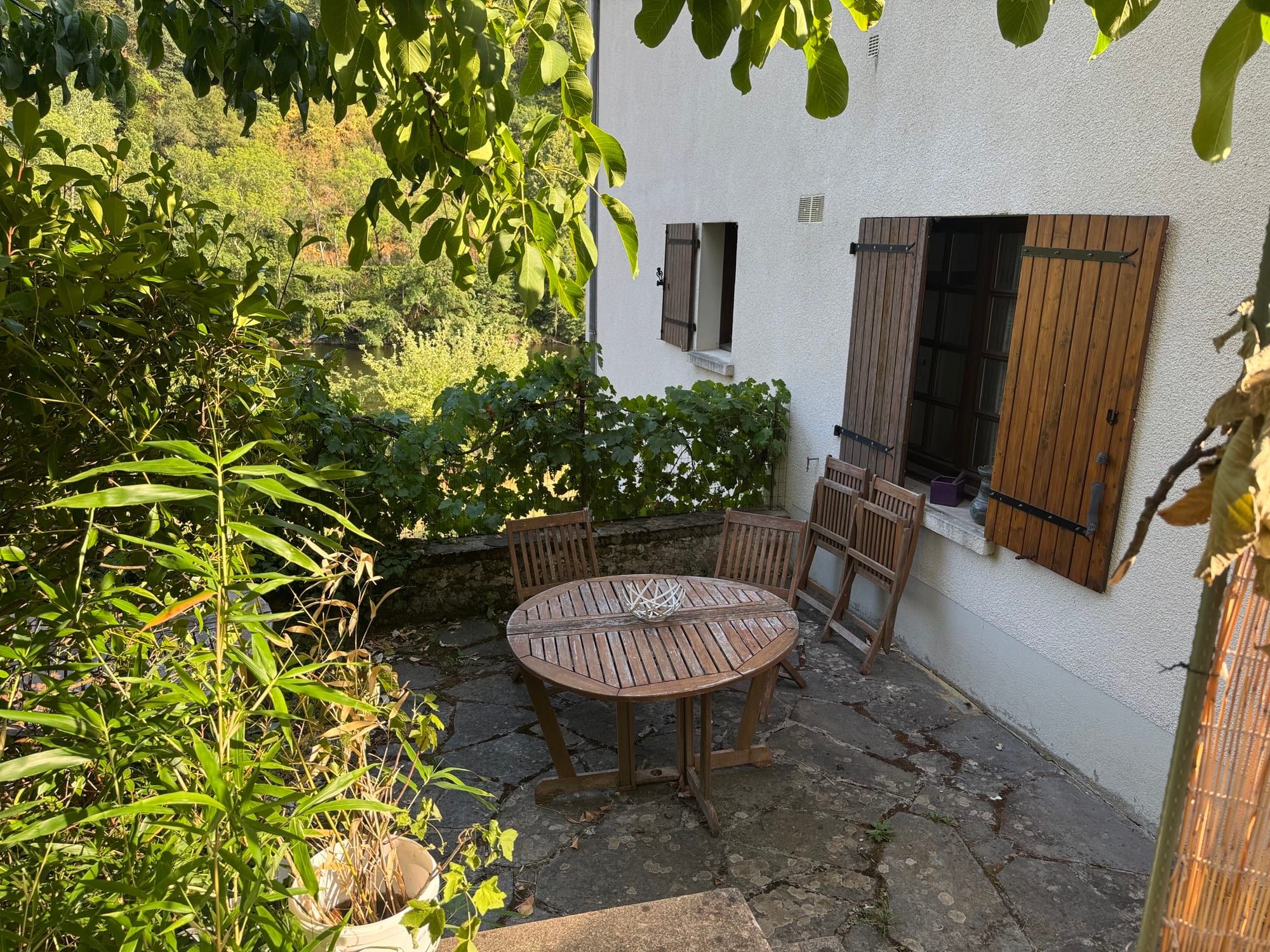 Terrasse privée ombragée du gîte, avec table en bois et chaises